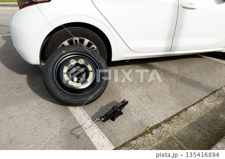 a temporary spare wheel resting on the car, ready to be changed 135416894