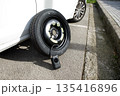 a temporary spare wheel resting on the car, ready to be changed 135416896