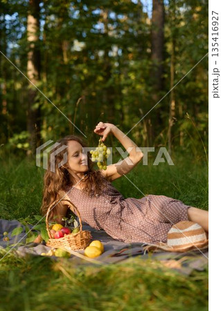 Woman in meadow, female posing with grapes in sunlit meadow Woman in meadow, female posing with grapes in sunlit meadow 135416927