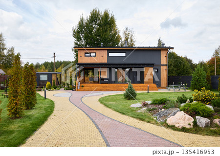 Modern wooden facade house featuring landscaped gardens and privacy fencing Modern wooden facade house featuring landscaped gardens and privacy fencing 135416953