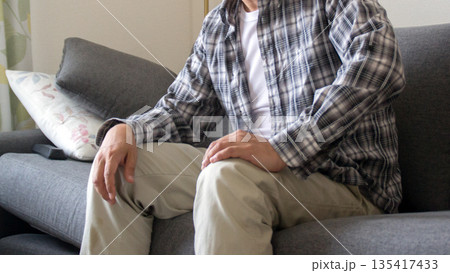 ソファーに座る落ち着かない中年男性 ソファーに座る落ち着かない中年男性 135417433