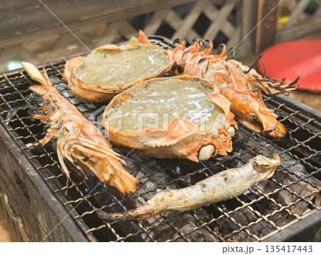 カニ味噌甲羅焼き、海鮮を焼き網で焼いている様子 135417443