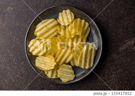 Wavy potato chips on black table. Top view. Wavy potato chips on black table. Top view. 135417952