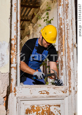 Worker carefully examining window frame with protective gear on 135418187