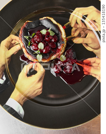 Hands sharing glossy cherry tart at celebratory dinner 135418190