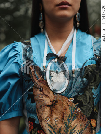 Softly lit portrait showcasing ornate necklace and textured fabric details 135418220