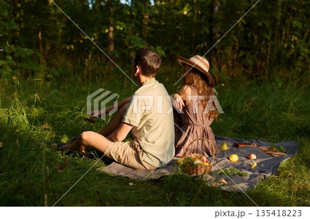 Couple lounging on blanket amid fruit and sunshine Couple lounging on blanket amid fruit and sunshine 135418223