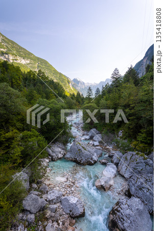 Turquoise Soca Isonzo River flowing through a rocky alpine gorge with clear water, boulders and green forest in Slovenia near Bovec Turquoise Soca Isonzo River flowing through a rocky alpine gorge with clear water, boulders and green forest in Slovenia near Bovec 135418808