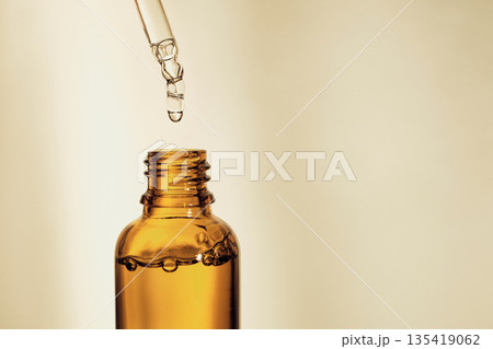 Dropper dispensing serum into amber bottle for skincare concept 135419062