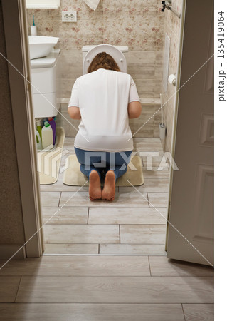 Woman kneeling in bathroom, experiencing morning sickness or illness Woman kneeling in bathroom, experiencing morning sickness or illness 135419064