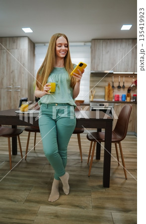 Happy morning in a bright kitchen with fresh juice and technology 135419923