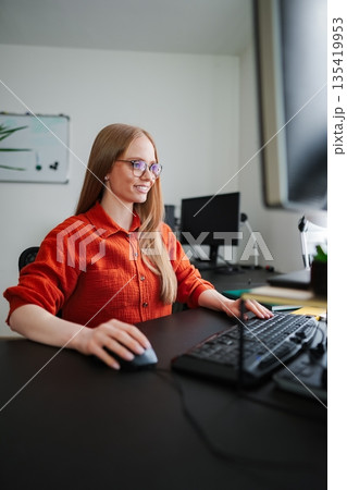 Focused professional at a desk working on a computer in a cozy office 135419953
