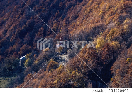 A mountain with a church and a house in the distance. Georgia 135420903