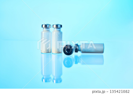 Medical vials containing vaccine powder on blue surface Medical vials containing vaccine powder on blue surface 135421082