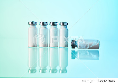 Medical vials containing powder reflecting on blue surface 135421083