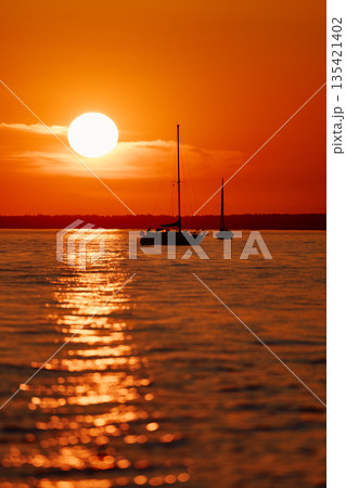 Sailing regatta in the Gulf of Finland at sunset, few sailing yachts competing in a race, splashing water from under the boats, teamwork, board the boat 135421402