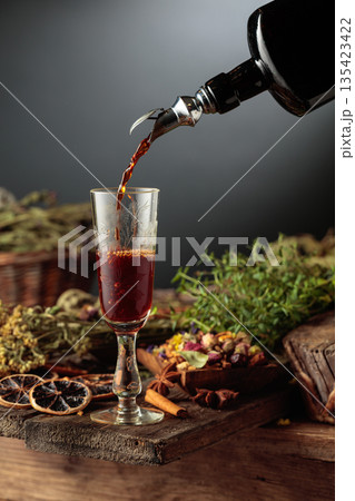 Herbal bitter liqueur is poured from a vintage bottle into a glass. 135423422