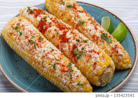 Delicious Mexican dish Elotes corn cob covered in spices and cheese Delicious Mexican dish Elotes corn cob covered in spices and cheese 135423591