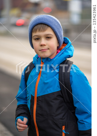 Boy in a blue hat and blue jacket on a city street, portrait of a child. Boy in a blue hat and blue jacket on a city street, portrait of a child. 135423961