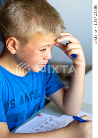 A boy in a blue T-shirt is crying over school. A boy in a blue T-shirt is crying over school. 135423986