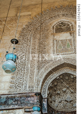 Intricate Islamic architecture of the Qalawun complex on Al-Muizz Street in Cairo. Detailed stone carvings and geometric patterns adorn the walls and windows. 135424041