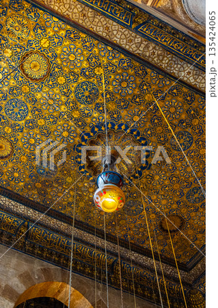 Intricate ceiling design of Madrasa Al-Kamil Ayyub in Cairo, featuring ornate patterns and hanging lamps. The vibrant colors and details reflect Islamic architecture. 135424065