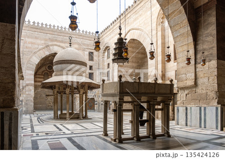 Interior view of Madrasa Al-Kamil Ayyub on Al-Muizz Street in Cairo. Features arches, decorative lanterns, and a central structure with intricate designs Interior view of Madrasa Al-Kamil Ayyub on Al-Muizz Street in Cairo. Features arches, decorative lanterns, and a central structure with intricate designs 135424126