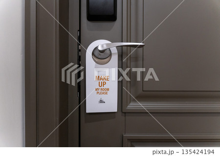 Hotel room door handle with a make up my room sign hanging on a modern interior door, neutral colors and minimal design Hotel room door handle with a make up my room sign hanging on a modern interior door, neutral colors and minimal design 135424194