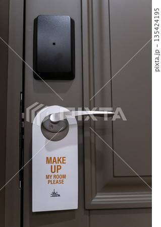 Hotel room door handle with a make up my room sign hanging on a modern interior door, neutral colors and minimal design Hotel room door handle with a make up my room sign hanging on a modern interior door, neutral colors and minimal design 135424195