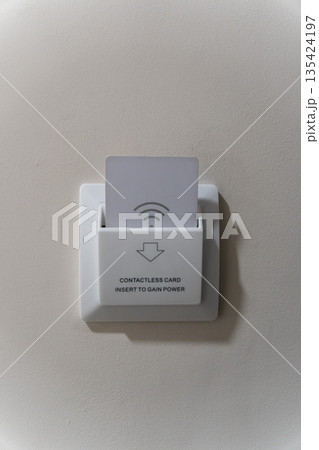 Hotel room key card power switch with contactless card inserted, mounted on a neutral beige wall, minimal and clean interior detail 135424197