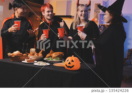 Friends enjoying a Halloween party at a bar making a toast 135424226