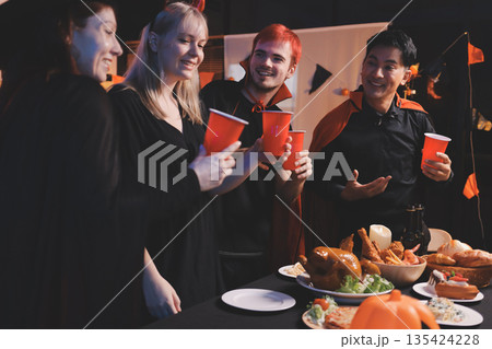 Friends enjoying a Halloween party at a bar making a toast 135424228