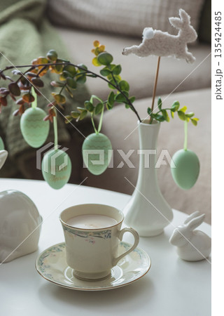 Spring Table Decor with Bunny Figurines, Hanging Eggs and Floral Cup of Coffee 135424485