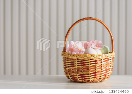 Wicker Easter Basket with Pastel Eggs and Flowers. Soft Spring Decor Wicker Easter Basket with Pastel Eggs and Flowers. Soft Spring Decor 135424490