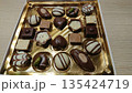 Assorted chocolate pralines in golden box on wooden table 135424719