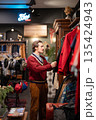 Stylish man customer picks trendy old fashioned outfit in fashionable selective second hand store. 135424943