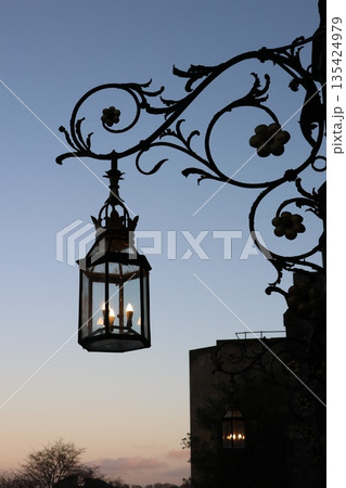Classic Iron Street Lamp on historic building facade, featuring ornate metalwork Classic Iron Street Lamp on historic building facade, featuring ornate metalwork 135424979