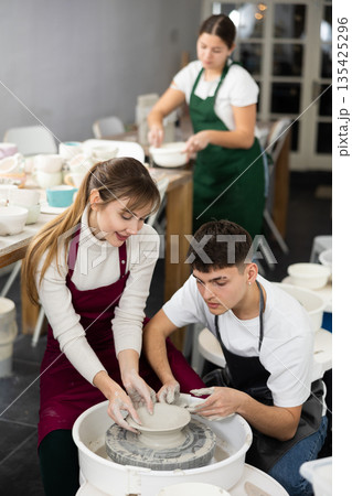 Young woman and young man sculpting product on potter's wheel 135425296