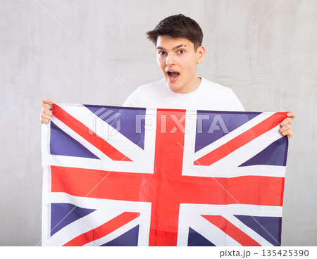 Surprised young guy holding UK flag 135425390