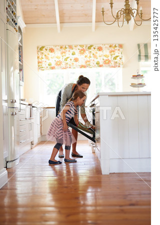 Mother, oven or kid baking in kitchen as a happy family with a young girl learning cookies recipe at home. Cake, girl baker or mom helping or teaching daughter to bake in stove for child development Mother, oven or kid baking in kitchen as a happy family with a young girl learning cookies recipe at home. Cake, girl baker or mom helping or teaching daughter to bake in stove for child development 135425777