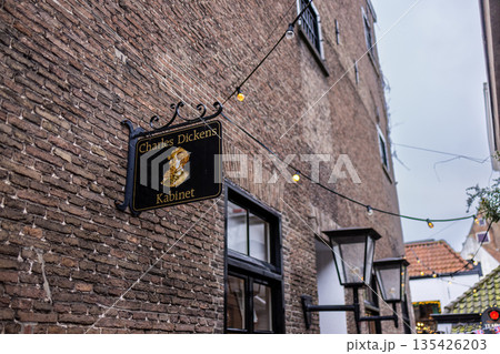 Decorative sign with golden profile hangs in festive alleyway with string lights and lanterns. Decorative sign with golden profile hangs in festive alleyway with string lights and lanterns. 135426203