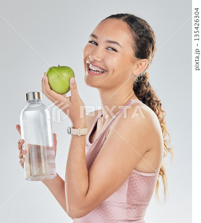 Portrait, woman and water bottle with apple in studio for diet of healthy food, nutrition and detox for weightloss. Happy female fitness model, hydration and fruit to lose weight on white background Portrait, woman and water bottle with apple in studio for diet of healthy food, nutrition and detox for weightloss. Happy female fitness model, hydration and fruit to lose weight on white background 135426304