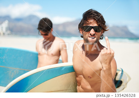 Beach, middle finger and man surfing friends outdoor together for summer vacation or holiday trip overseas. Surf, sea or rude with a young male surfer in sunglasses and friend bonding at the coast 135426328