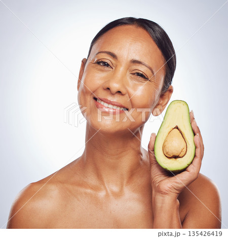 Face, skincare and senior woman with avocado in studio isolated on a white background. Portrait, natural fruit and happy model with food for organic nutrition, healthy diet and omega 3 for anti aging 135426419