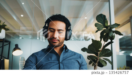 Man, thinking and contemplation in office with headphones for podcast, music or listening to broadcast. Person, reflection or daydream in workplace with audio tech, streaming service or online radio. 135426757