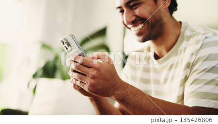 Phone, relax and man on sofa in home for texting, social media or chatting on mobile app. Happy, technology and male person with cellphone for communication, connection or networking in living room. 135426806