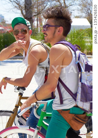Men, students and friends with back, bicycle and sustainable transportation on road in summer sunshine. Young gen z people, retro bike and outdoor together in street with travel on university campus Men, students and friends with back, bicycle and sustainable transportation on road in summer sunshine. Young gen z people, retro bike and outdoor together in street with travel on university campus 135426830