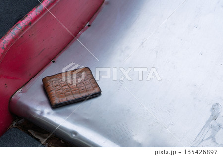 Brown leather wallet with crocodile texture on a scratched metal surface. Lost item concept with copy space 135426897