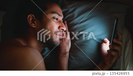 Night, man and lay in bed with phone for text message reply, social media and check dating site. Late, person and scroll with technology in apartment for online conversation, internet and mobile app. 135426955