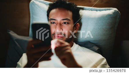 Night, man and scroll in bedroom with phone for text message reply, social media and watching video. Late, person and browse with tech in apartment for online conversation, internet and mobile app. Night, man and scroll in bedroom with phone for text message reply, social media and watching video. Late, person and browse with tech in apartment for online conversation, internet and mobile app. 135426978